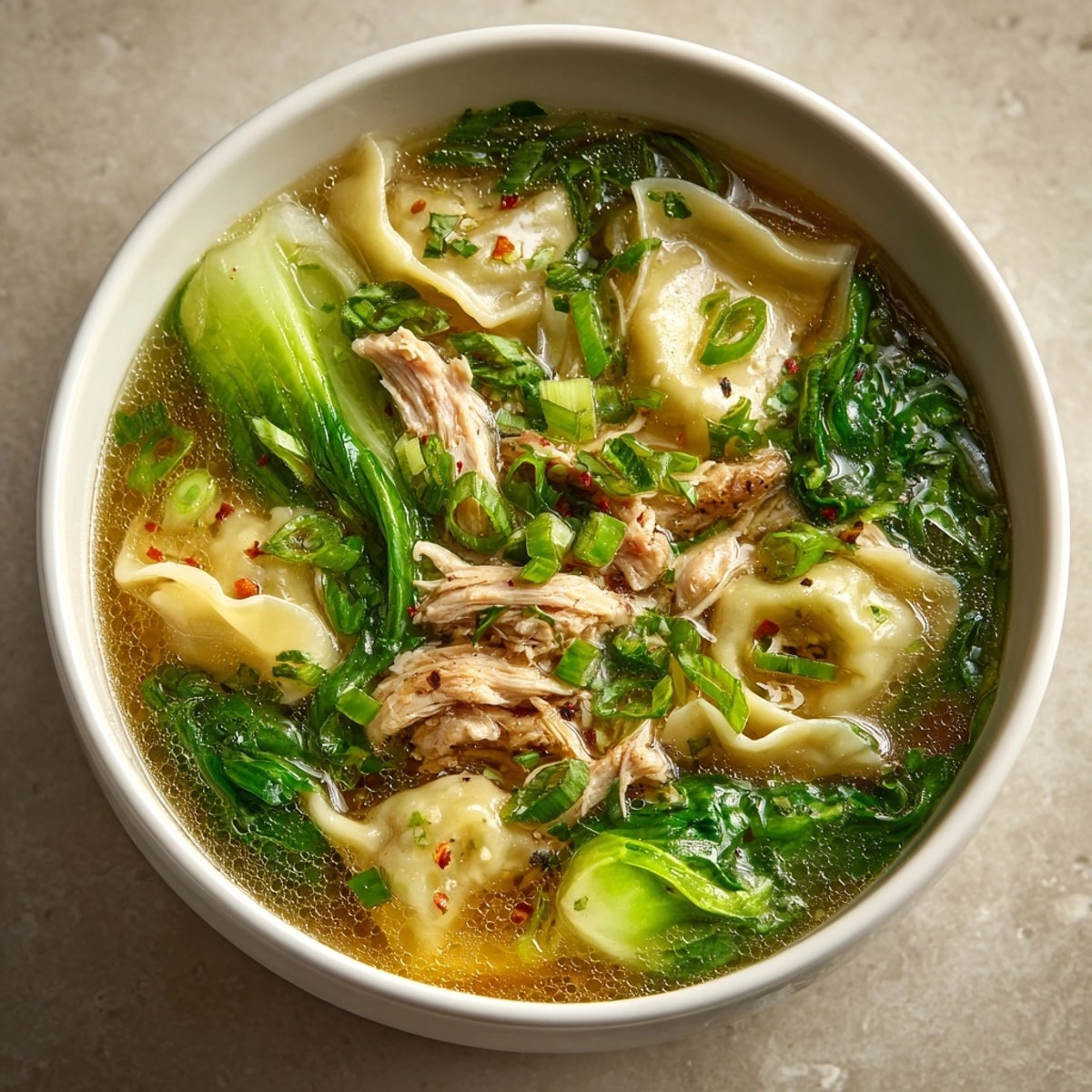 Steaming bowl of Simplified Wonton Soup with chicken, bok choy, and crispy wonton strips.