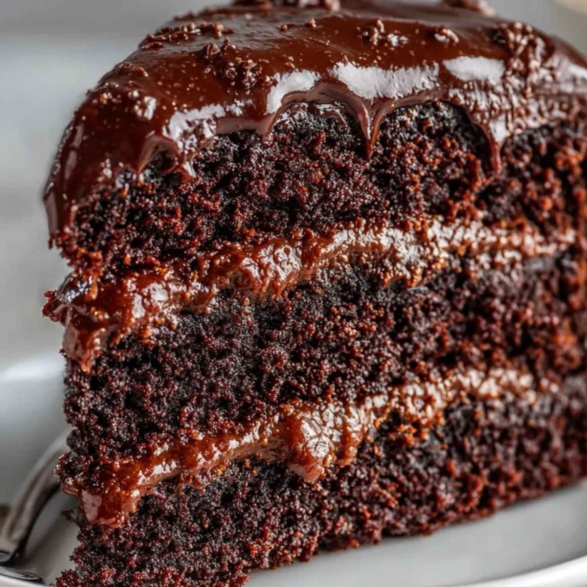 Three-layer Matilda Chocolate Cake slathered in rich, glossy fudge frosting ready to be served.