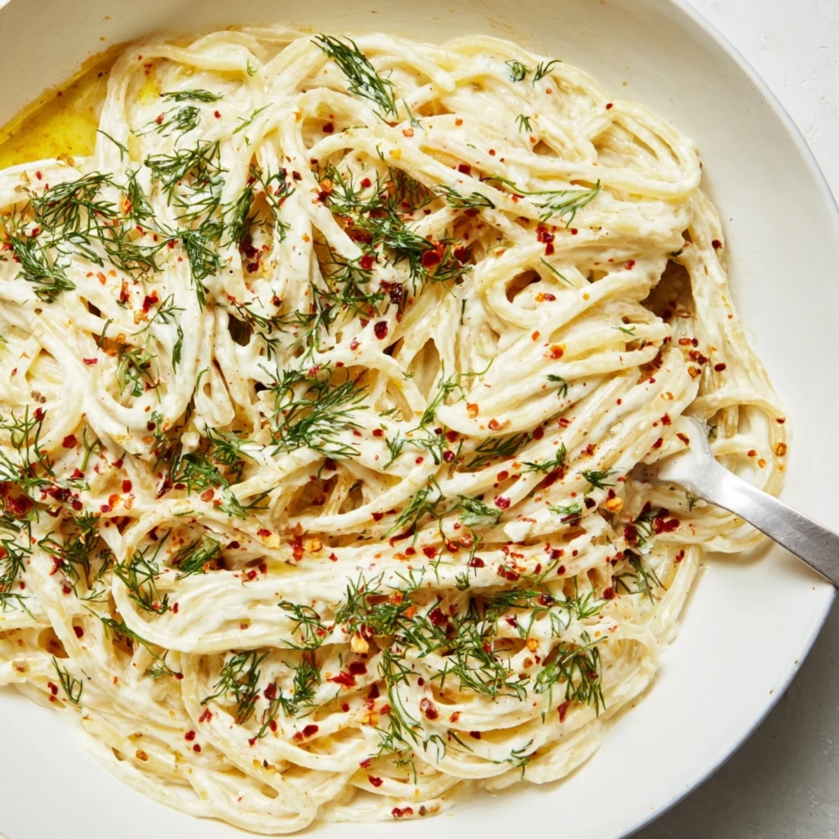 Delicious Turkish garlic yogurt pasta, garnished with dill and parsley for freshness.