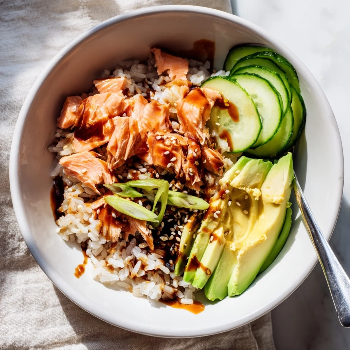 A vibrant Leftover Salmon & Rice Bowl topped with fresh avocado and cucumbers.  