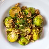 Golden roasted maple glazed Brussels sprouts with crunchy walnuts, ready for serving warm.