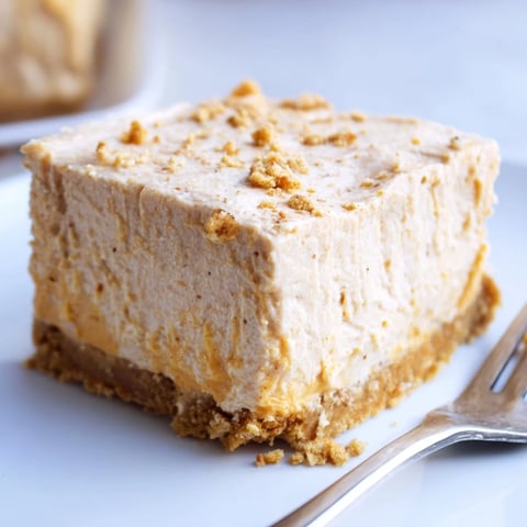 Creamy pumpkin spice cheesecake bars drizzled with caramel, perfect for fall gatherings.  